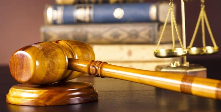 gold scales of justice, bankruptcy and workers' compensation law books, wooden legal mallet on desk.