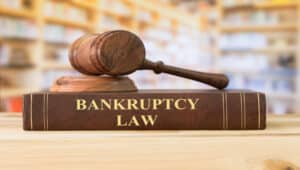 A brown book titled "bankruptcy law" and brown wooden gavel sitting on a desk in a library