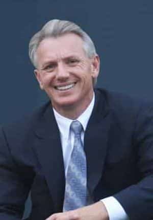 Lawyer Tony Turner white male, grey hair, smiling, blue suit, white collared shirt and blue tie